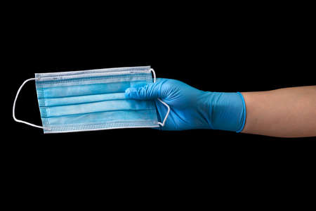 Doctors hand in medical gloves wearing a mask isolated on blackの写真素材