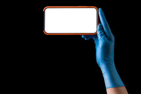 Doctor's hand in sterile medical gloves holding phone isolated on black background with clipping...