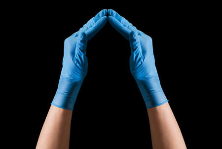 Doctors hand in sterile medical gloves showing heart shape isolated on black