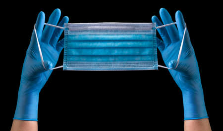 Doctors hand in medical gloves wearing a mask isolated on black