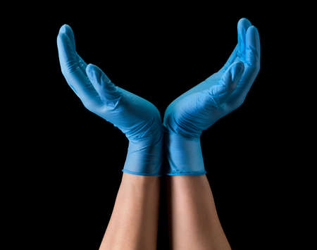 Doctors hand in sterile medical gloves hold earth shape isolated on black