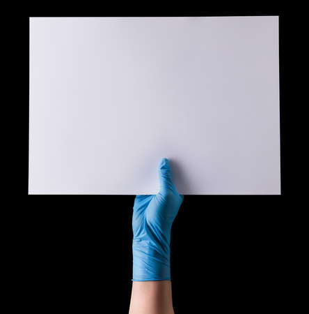 Doctor's hand in sterile medical gloves holding banner isolated on black background . Concept of protection against pandemic and massage Stay at home.の写真素材