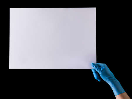 Doctor's hand in sterile medical gloves holding banner isolated on black background with clipping path. Concept of protection against pandemic and massage Stay at home.の写真素材