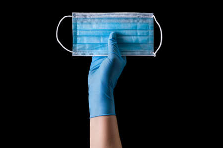 Doctor's hand in medical gloves wearing a mask isolated on black background with clipping path....