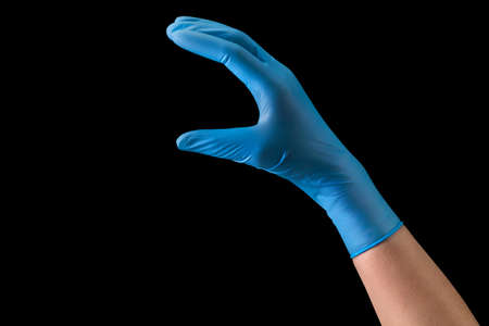 Doctor's hand in sterile medical gloves holding something with two fingers isolated on black background with clipping path. Concept of protection against pandemic and viruses.の写真素材