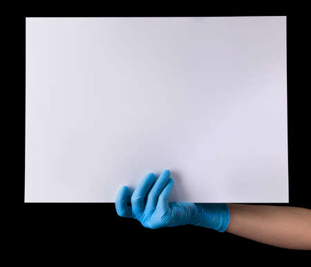 Doctor's hand in sterile medical gloves holding banner isolated on black background with clipping path. Concept of protection against pandemic and massage Stay at home.の写真素材