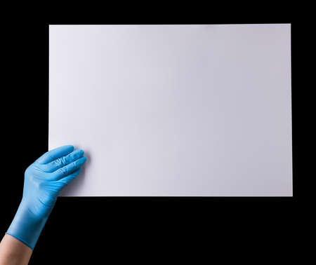 Doctor's hand in sterile medical gloves holding banner isolated on black background with clipping...