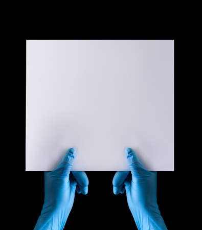 Doctor's hand in sterile medical gloves holding banner isolated on black background with clipping path. Concept of protection against pandemic and massage Stay at home.の写真素材