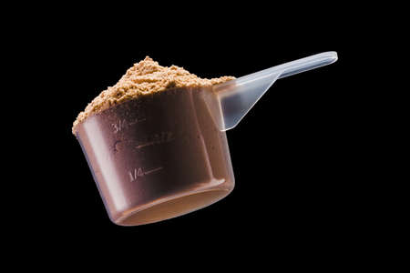 A scoop of chocolate protein powder drink isolated on black backgroundã Concept of fitness supplementの写真素材