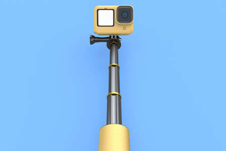 Photo and video lightweight yellow action camera with selfie stick on blue background. 3D rendering of professional photography equipment for sportsmen and travelの写真素材