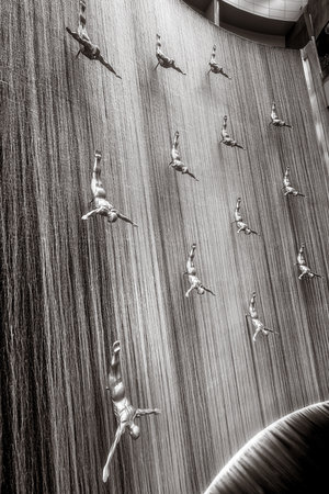 Famous Waterfall with art fiberglass sculptures of human divers in Dubai Mall, UAE.