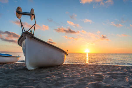 Boat fishing . wooden boat . old boat . sunset boat . sunset beach . beach sand . boat in beach sand . boat in mediterranean sea . sunset mediterraneanの写真素材