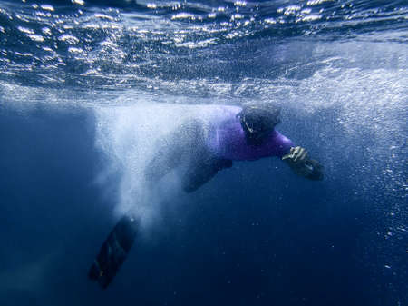 A young man swimming underwater with sea bubbles and a blue sea in the Mediterranean Sea. Dive among the water bubbles under the blue sea. swimming man underwaterの写真素材