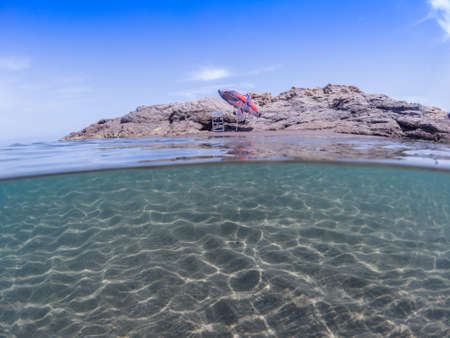 Half under the water and half for the beach with an umbrella, Tranquil beach scene. Exotic tropical beach landscape for background or wallpaper. Design of summer vacation holiday concept. summer beachの写真素材