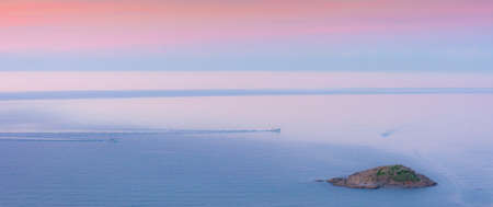 Aerial view of an island and around it boats with sunset in the spring, Jijel, Mediterranean sea, spending a summer vacation in Mediterranean, traveling to algeria afric, Blue sea and orange sky.の写真素材