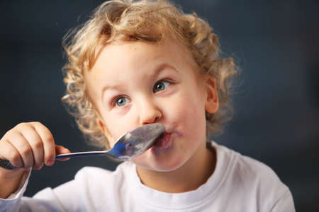 Portrait of the little boy eating yogurtの写真素材