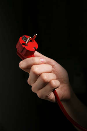 Hand holding power plug isolated on black backgroundの写真素材