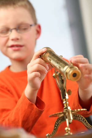 Boy is looking through a classic telescopeの写真素材