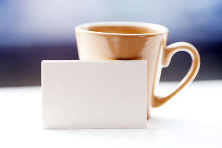 Business card on windowsill against a cup, city view behind.の写真素材
