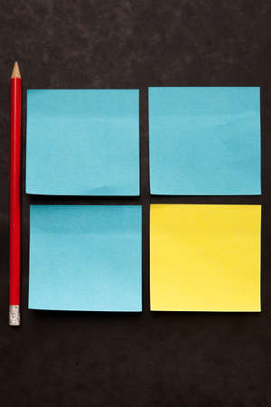 Yellow and blue stick notes with pencil on black background.の写真素材