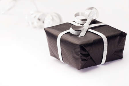 Black gift box with silver bow on light background.の写真素材