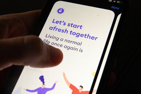 Coronavirus tracking app on a mobile smartphone. Close up of woman's hand holding smartphone screen...