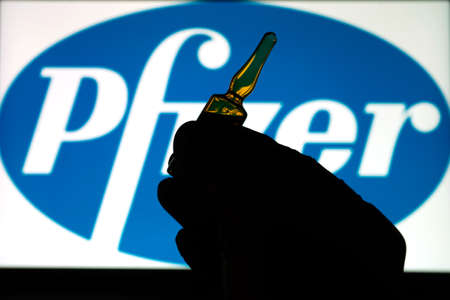 Pfizer coronavirus vaccine pharmaceutical corporation. Pfizer logo with hand holding vaccine.