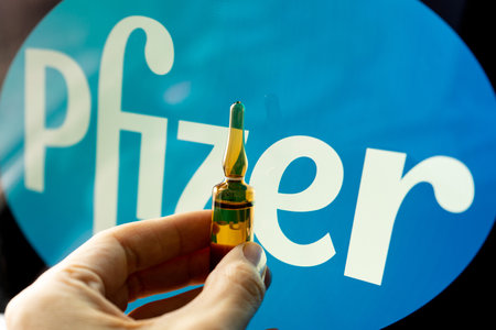 Pfizer coronavirus vaccine pharmaceutical corporation. Pfizer logo with hand holding vaccine.