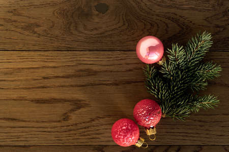 Christmas decoration, a branch of fir tree with three pink baubles on rustic wooden background. Holiday time theme for Christmas and New Yearの写真素材