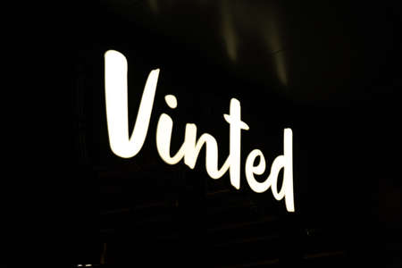 Shiny Vinted logo sign at night. New Vinted office in Vilnius. Vinted is a Lithuanian online marketplace for used clothes, shoes and accessoriesのeditorial素材