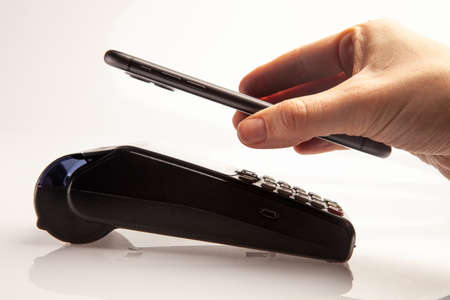 Contactless payment during coronavirus pandemic. Female customer is paying using phone and payment...
