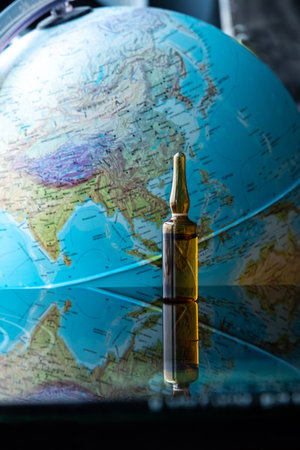 A set of vaccines, syringes and lab equipment in front of the globe.