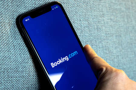 Hands holding iPhone 11 with app of booking.com service. Smartphone, travel and hotel industry in crisis due to Covid or Coronavirus pandemic.のeditorial素材
