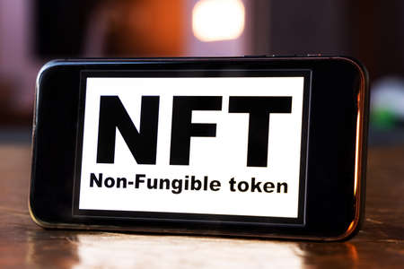 NFT non - fungible tokens black inscription on phone screen. A non-fungible token (NFT) is a special type of cryptographic token which represents something unique.の写真素材
