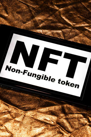 NFT non - fungible tokens black inscription on phone screen. A non-fungible token (NFT) is a special type of cryptographic token which represents something unique.の写真素材