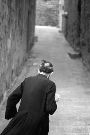 Rear view of Priest walking through alley way with key in hand. Victoria, Gozo, Malta, Europe.の写真素材