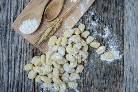 Gnocchi on Cutting Board and Rustic Wooden Backgroundの写真素材