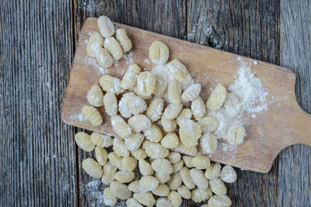 Gnocchi on Cutting Board and Rustic Wooden Backgroundの写真素材