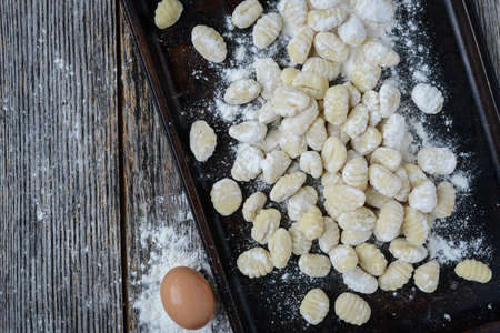 Gnocchi on Cookie Sheet and Rustic Wood Backgroundの写真素材