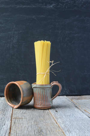 Raw Spaghetti in Earth Wear on Rustic Wooden Backgroundの写真素材