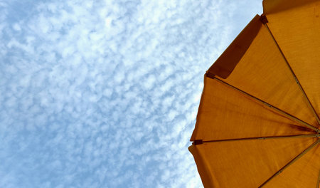 Yellow umbrella against the blue sky with white clouds. Horizontal picture.の写真素材