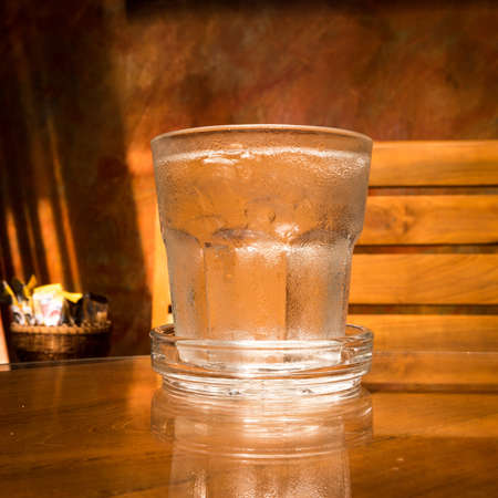 Glass of water and ice on brown wooden tableの写真素材