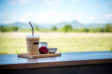 Cold coffee on a wooden table and background landscape.の写真素材
