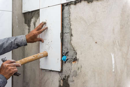 Ceramist puts tile on the wall. Professional ceramist is laying ceramic tile on the wallの写真素材