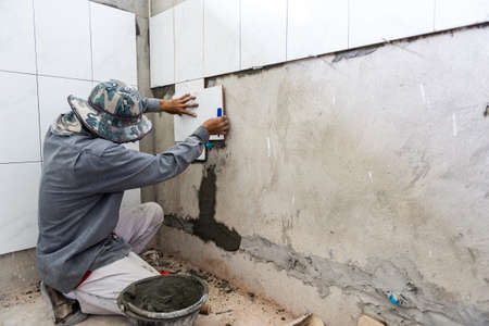 Ceramist puts tile on the wall. Professional ceramist is laying ceramic tile on the wallの写真素材