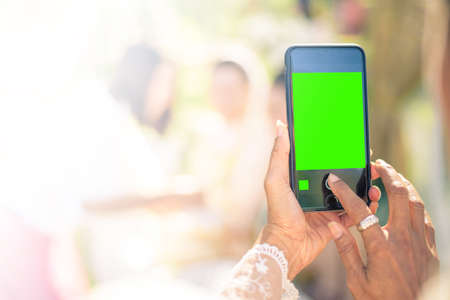 People use smart phone to take photographs in Thai wedding ceremony. (green screen at smart phones)の写真素材
