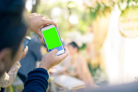 People use smart phone to take photographs in Thai wedding ceremony. (green screen at smart phones)
