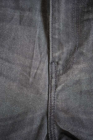 Closeup denim jeans texture. Stitched textured black denim jeans background.