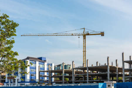 construction site with cranes towering into bright blue sky with puffy white cloudsの写真素材
