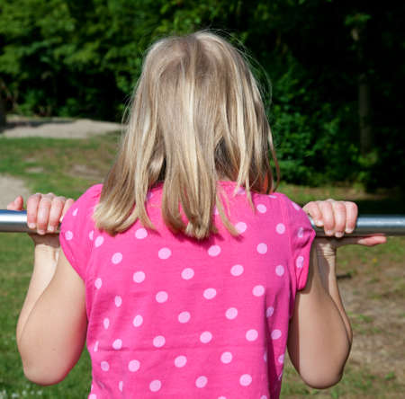 girl hanging on horizontal bar